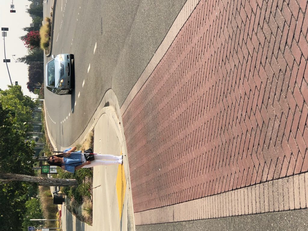 Blind person waiting at the curve preparing to cross the street